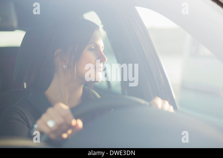 Giovane imprenditrice guardando attraverso la finestra mentre si guida auto Foto Stock