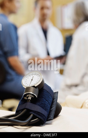 La pressione sanguigna manometro con il team medico di discutere in background Foto Stock