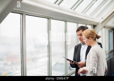 La gente di affari con tavoletta digitale in corrispondenza della finestra di office Foto Stock