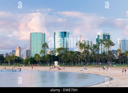 Skyline di Honolulu oltre la spiaggia di Ala Moana Beach Park, Hawaii, al tramonto Foto Stock