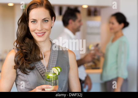 Donna sorridente holding bicchiere da cocktail con gli amici al bar Foto Stock