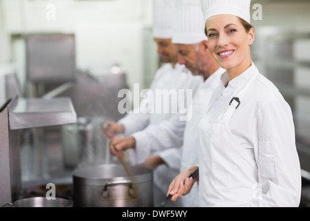 Lo chef felice sorridente in telecamera durante la cottura in stufa Foto Stock