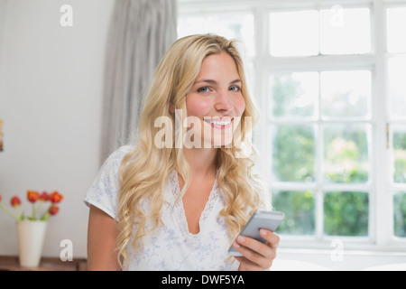 Ritratto di una donna la lettura di un messaggio di testo a casa Foto Stock
