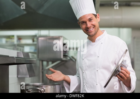 Lo Chef tenendo un coperchio sorridente in telecamera Foto Stock