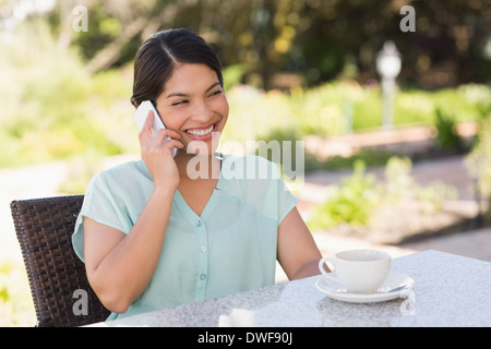 Sorridente imprenditrice avente un caffè parlando al telefono Foto Stock