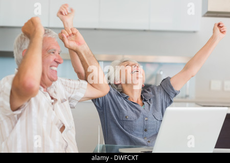 Emozionato coppia senior utilizzando il portatile al tavolo Foto Stock