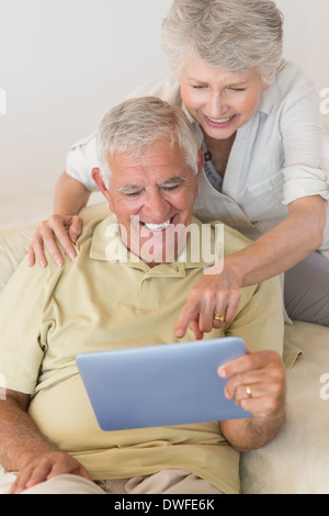 Allegro coppia senior utilizzando la tavoletta digitale insieme Foto Stock