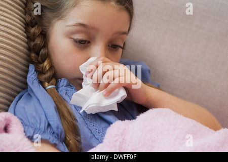 Giovane ragazza soffia il naso con carta velina Foto Stock