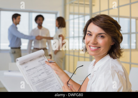 Imprenditrice sorridente con i colleghi si stringono la mano in ufficio Foto Stock