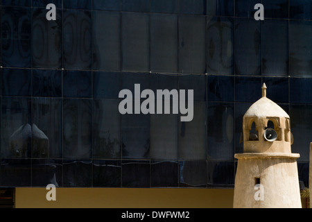 Minareto tradizionale torre in Qatar con un ufficio moderno blocco dietro Foto Stock