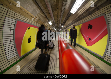I pendolari passano davanti a un annuncio pubblicitario per l'Apple iPhone 5c esposto sulla parete di una stazione della metropolitana sulla metropolitana di Londra, Regno Unito. Esempio di pubblicità tecnologica dei primi anni '2010 nei trasporti pubblici Foto Stock