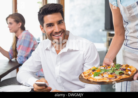 Cameriera dando la pizza in un uomo sorridente al coffee shop Foto Stock