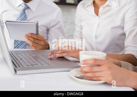 La sezione centrale di tre persone di affari con computer portatile Foto Stock