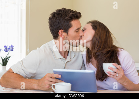 Paio di baciare mentre usando tavoletta digitale Foto Stock
