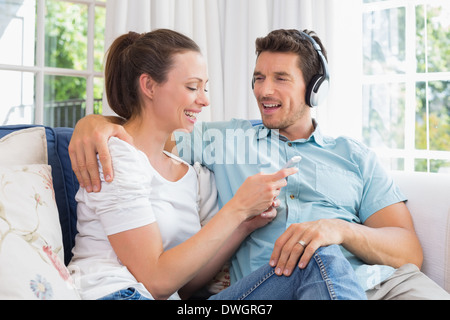 Giovane ascoltando musica con il telefono cellulare sul lettino Foto Stock