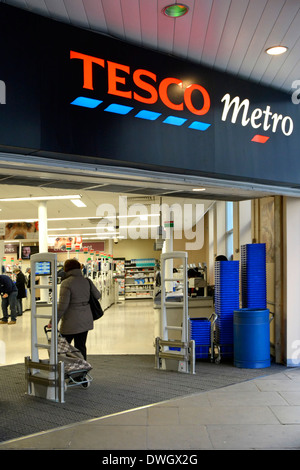 Shopping con carrello per lo shopping entrando Tesco Metro supermercato cibo negozio di alimentari negozio di affari nella zona principale degli uffici città di Londra Inghilterra Regno Unito Foto Stock