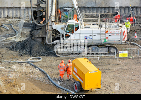 Sito in costruzione con volo continuo della coclea rig di palificazione al lavoro su nuove basi con completato impilati a parete di ritegno al di là Foto Stock