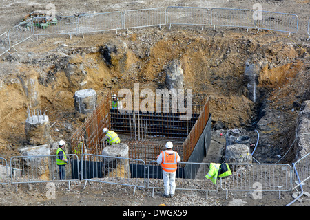 Fissatori di acciaio ponendo le aste di rinforzo nella gabbia di fondazione attorno ai pali prima della colata del calcestruzzo Foto Stock