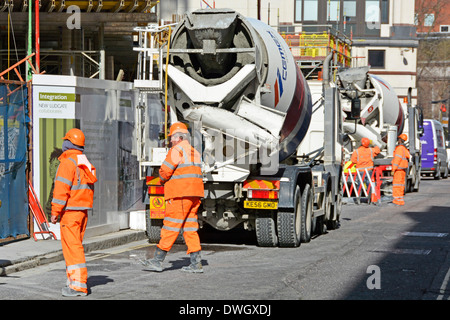 Le sale commerciali di traffico sul cantiere di costruzione supervisionano il flusso di traffico per gli autocarri in cemento che scaricano con gru sull'autostrada pubblica Londra UK Foto Stock