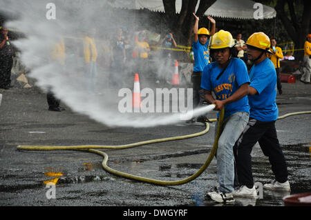 Metro Manila, Filippine - Marzo 8, 2014: Vigili del fuoco in possesso di un tubo flessibile che mira a un obiettivo di mettere alla prova la loro abilità al Corpo Nazionale dei Vigili del Fuoco delle gare che si terranno presso il giardino Mehan Park di Manila il sabato. Filippine osservata la prevenzione antincendio di questo mese di marzo. (Foto di Jay Ganzon / Pacific Press/Alamy Live News) Foto Stock