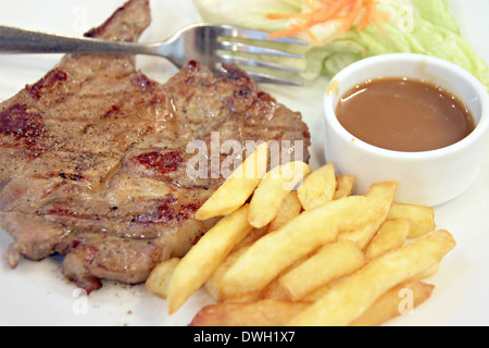 Bistecca di carne di maiale con patate fritte nel piatto. Foto Stock