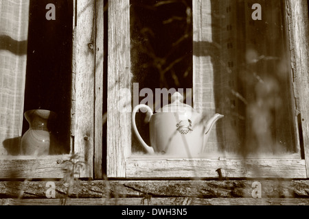 Pot del caffè nella finestra di un vecchio log-house. Fotografia in bianco e nero, seppia oscurata. Foto Stock