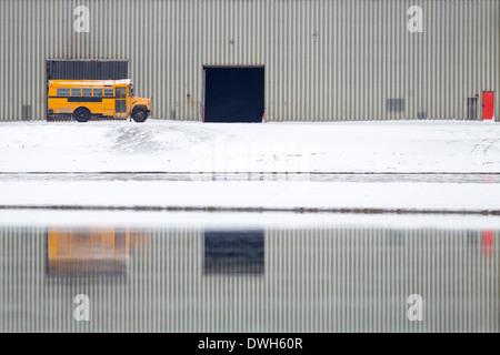 Scuola bus parcheggiato parcheggiato nella parte anteriore del gancio del velivolo con la riflessione, Kaktovik, Alaska nel mese di ottobre. Foto Stock