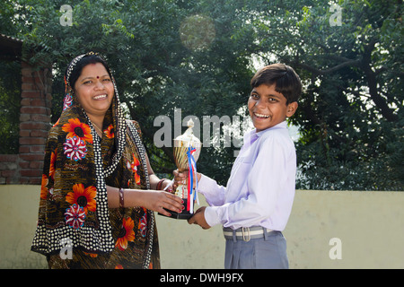 Donna indiana dando trofeo per bambini Foto Stock