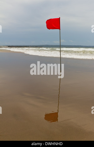 La stagione delle tempeste. Bandiera rossa sulla spiaggia Foto Stock