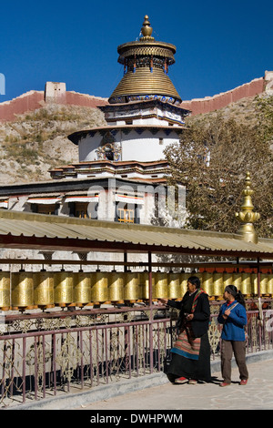 Pellegrini buddista girare le ruote di preghiera presso il Kumbum vicino monastero Palcho nella città di Gyantse in Tibet. Foto Stock