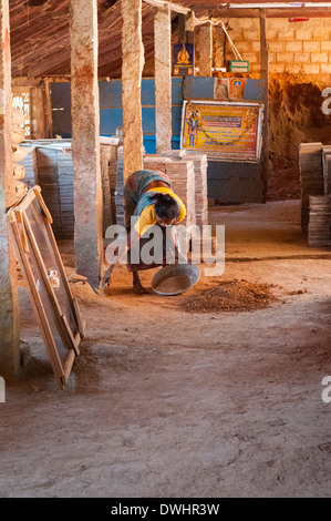 L' India , il Tamil Nadu , Chettinad , Karakaikudi piastrelle fatte a mano vecchia fabbrica donna donna femmina raccoglie la sabbia per calcestruzzo cementizio Foto Stock