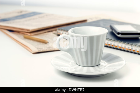 Tazza di caffè notebook con quotidiani sulla scrivania bianca Foto Stock