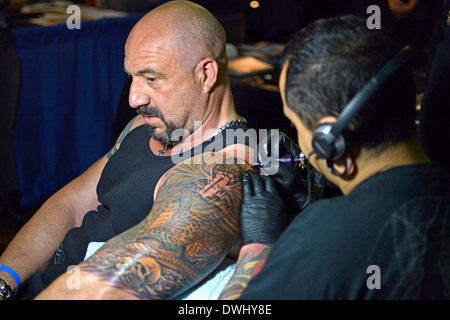 Uomo di ottenere un braccio grande tattoo a Tattoo Convention di New York a Manhattan presso la sala da ballo di Roseland Foto Stock