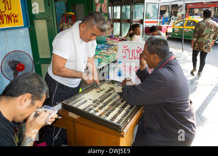 Uomo tailandese scegliendo amuleto al shop Foto Stock