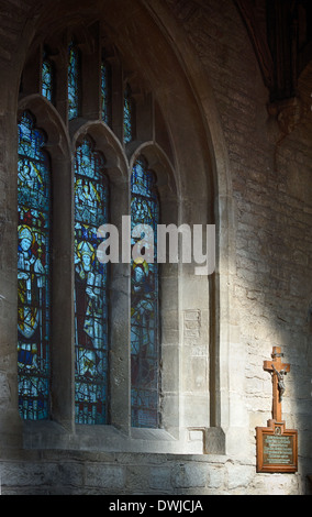 Le finestre di vetro macchiate e Cristo sulla croce nella luce solare a San Giovanni Battista, burford, Cotswolds, Oxfordshire, Inghilterra Foto Stock