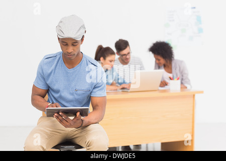 Artista con tavoletta digitale con i colleghi in background in ufficio Foto Stock