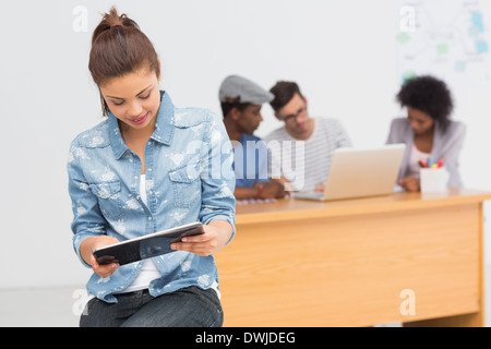 Artista con tavoletta digitale con i colleghi in background in ufficio Foto Stock