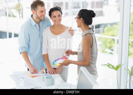 Interior designer che mostra la ruota dei colori a felice i giovani clienti Foto Stock