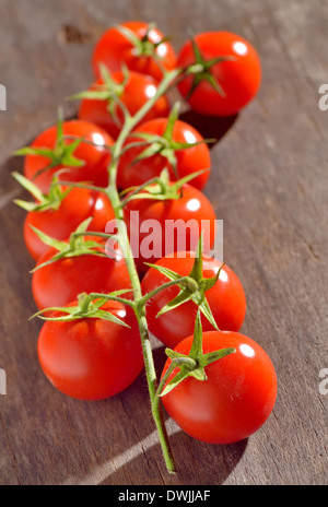 Ramo di pomodori ciliegia isolato su un tavolo di legno Foto Stock