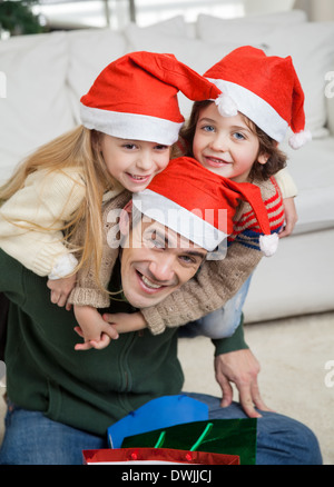 Padre Piggybacking i bambini durante il periodo di Natale Foto Stock