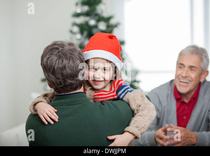 Felice ragazzo abbracciando il padre durante il periodo di Natale Foto Stock