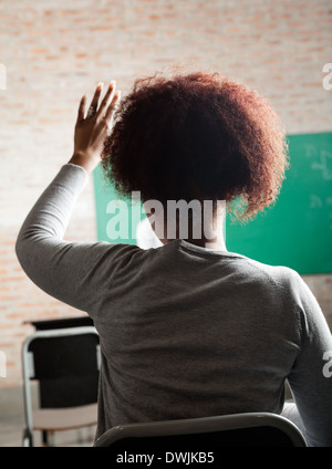 Studentessa alzando la mano per rispondere in Aula Foto Stock