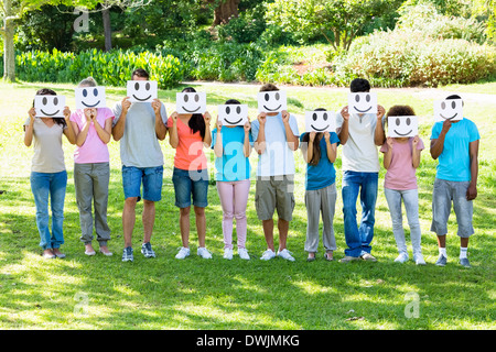 Amici multietnica holding smiley in posizione di parcheggio Foto Stock