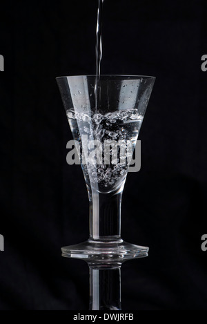 L'acqua versata in un bicchiere Foto Stock