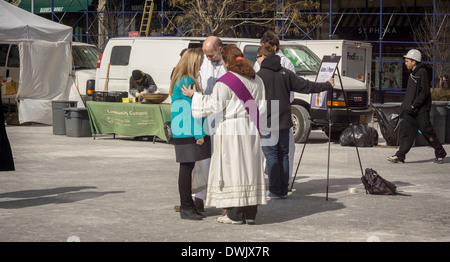 Clero da Gustavo Adolfo Chiesa Luterana in Union Square Park a New York pregare e ungerai con ceneri il Mercoledì delle Ceneri Foto Stock