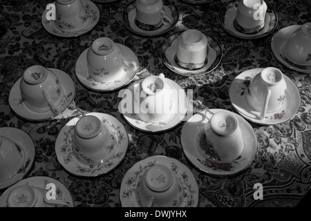 Teacups capovolto sul loro piattini su una tovaglia modellato. Foto Stock