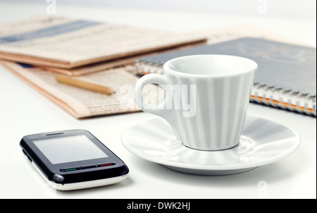 Tazza da caffè con giornali e smart phone sul tavolo per ufficio Foto Stock