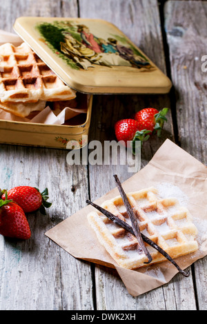 Cialde fresche con bastoncini di vaniglia e fragole servite con vintage scatola di metallo sopra il vecchio tavolo in legno Foto Stock