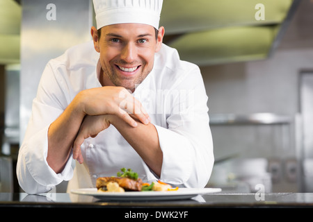 Sorridente chef maschio con cibi cotti in cucina Foto Stock