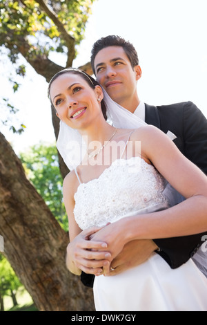 Riflessivo coppia di novelli sposi in piedi in giardino Foto Stock